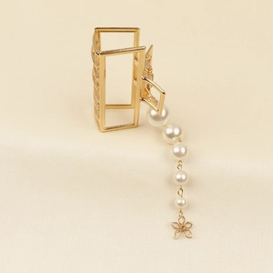 Détail de la pince à cheveux dorée avec perles élégantes et pendentif fleur délicat
