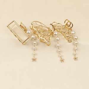 Détail de pinces à cheveux dorées avec pompons en perles, formes rectangle, papillon et fleur