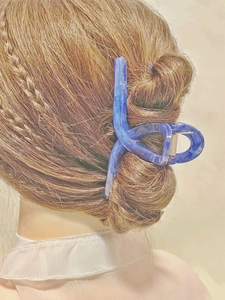 Blue marble textured acetate hair claw clip holding long brown hair in a bun updo