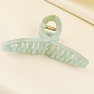 Detailed close-up of large matte acetate hair claw clip with green marble texture