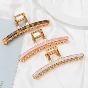 Detailed view of three large metallic hair claws with stylish resin marble patterns