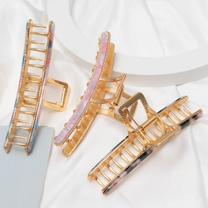 Elegant metal hair claws with colorful acetate marble patterns on white silk fabric