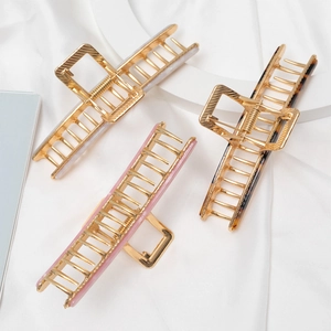 Three large metal hair claws in pink, white, and tortoiseshell resin for women's styling