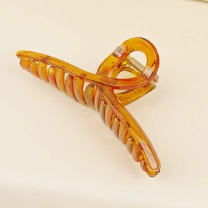 Detailed close-up of amber resin hair claw clip with strong metal spring and crossed teeth
