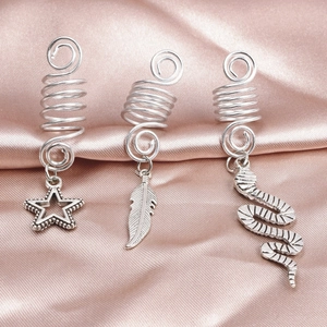 Détail de bijoux de cheveux argentés avec étoile, plume et serpent sur du satin