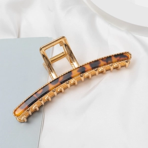 Macro shot of large golden metal claw clip with elegant tortoiseshell resin inlay