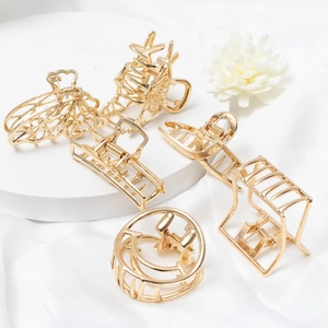 Elegant set of six golden geometric metal hair claws displayed on white silk backdrop