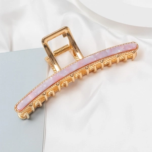 Detailed macro view of large gold claw clip with pink marble resin inlay and sturdy metal spring