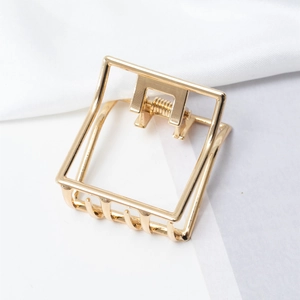 Detail of a minimalist gold hollow square metal hair claw clip with strong spring