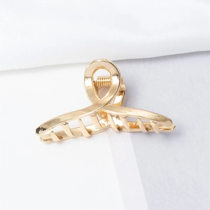 Detailed macro view of a shiny gold metal hair claw clip with a strong spring and teeth