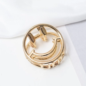 Detail of golden minimalist metal hair claw with hollow smile design on white silk