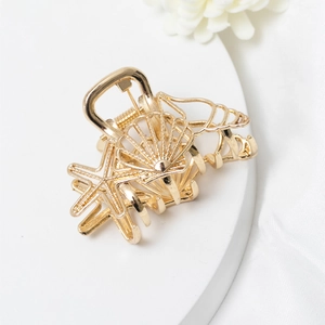 Detail shot of golden metal hair claw clip featuring seashell and starfish hollow design