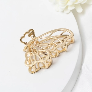 Elegant gold butterfly metal hair claw clip displayed on a minimalist white stone base