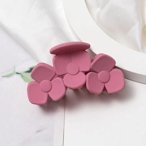 Gros plan d'une pince à cheveux rose mat Morandi avec motif à trois fleurs sur satin