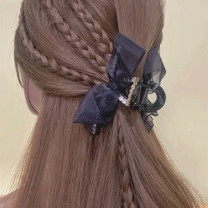 Détail d'une grande pince à cheveux en organza noir avec strass et chaîne dorée