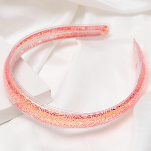 Gros plan détaillé du serre-tête transparent rempli de paillettes roses et dorées