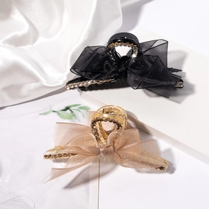 Détail de la pince à cheveux noeud en organza avec strass et chaînes sur tissu blanc