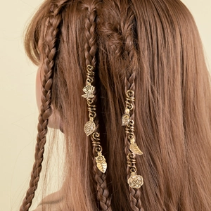 Close-up of golden spiral hair clip with rose pendant on a brown braided ponytail