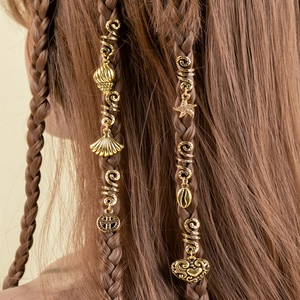 Close-up of golden dreadlock hair rings with sea shell and star charms on braided hair