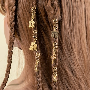 Golden spiral hair jewelry with charms like angel wings and dancers on dark braided hair
