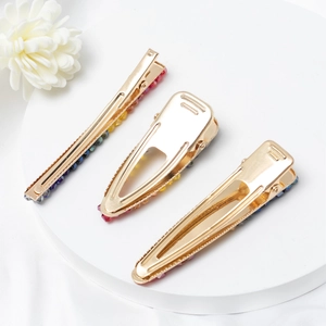 Set de barrettes dorées avec strass colorés sur un support de présentation blanc