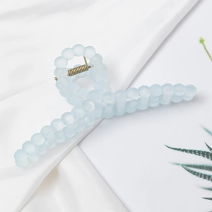 Light blue matte twisted hair claw clip with rounded bead design on white silk fabric