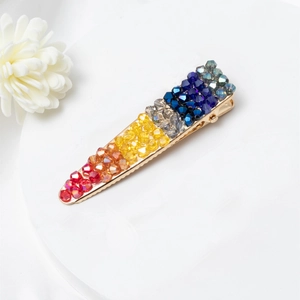 Détail des perles en cristal coloré sur une barrette en métal doré à dégradé