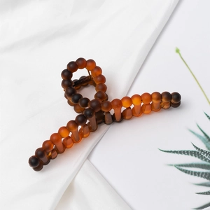 Detail of amber gradient hair claw clip with frosted beaded texture and metal spring