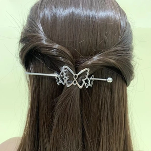 Detailed view of a silver metal butterfly hair pin styled in long dark hair