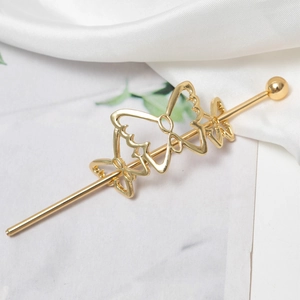 Close-up of golden alloy butterfly hair pin with hollow texture on white silk fabric