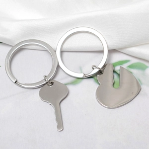 Polished stainless steel heart and key couple keychain set on white textured background
