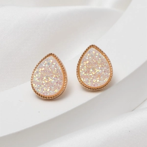 Macro detail of rose gold teardrop earrings with white crystal druzy on silk fabric