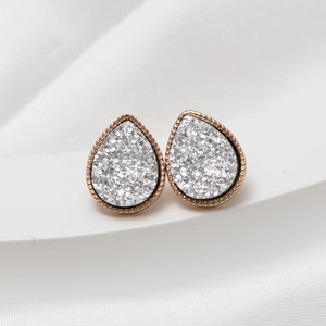 Close-up of teardrop stud earrings with rose gold beaded edge and shimmering grey crystals