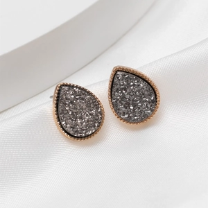 Macro shot of teardrop earrings with dark crystal cluster and rose gold grooved edges