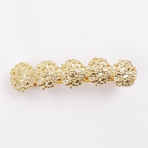 Detailed macro view of the golden spring hair clip with ornate lava-textured round carvings