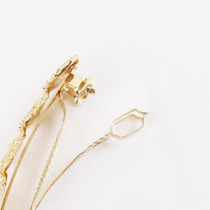 Close-up of the metal spring mechanism and textured gold surface of the circular hair clip