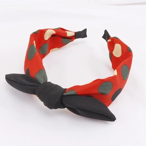 Gros plan d'un serre-tête en tissu rouge à pois avec un détail de nœud noir élégant