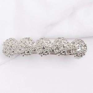 Detail view of silver spring hair clip with five textured circular metal elements