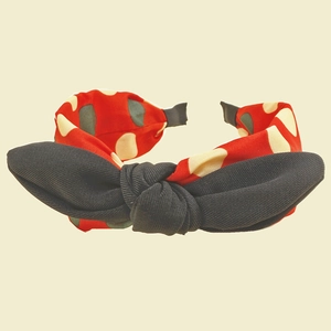 Détail d'un serre-tête rouge à pois avec un grand nœud décoratif en tissu noir