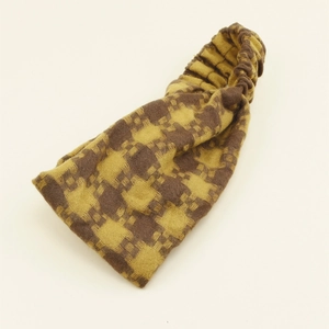 Close-up of vintage yellow and brown checkered knitted headband with elastic texture