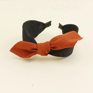 Détail d'un serre-tête avec nœud en tissu orange-brun et noir pour petites filles