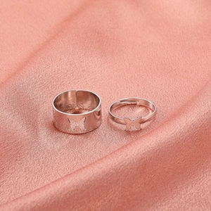 Macro shot of butterfly couple rings set with hollow out design on pink silk fabric