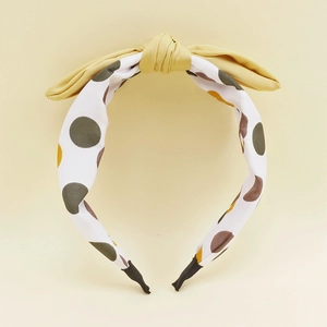 Détail d'un serre-tête en tissu pour enfants avec motif à pois et un nœud jaune décoratif