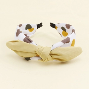 Détail du serre-tête avec nœud jaune moutarde et bandeau à motif de pois colorés