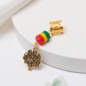 Détail d'un tube métallique doré évidé et d'un pendentif branche pour tresses dreadlocks
