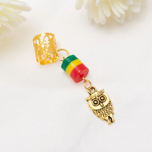 Vue détaillée d'un pendentif pour cheveux hibou doré avec des perles rouges jaunes vertes