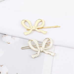 Vue détaillée de deux barrettes papillon en métal doré avec finition émail crème doux