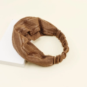 Close-up of a brown knit headband with hollow lace texture and front twist detail