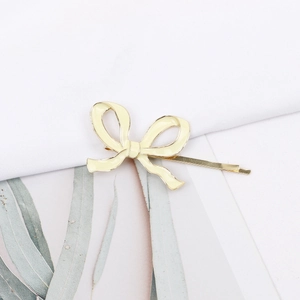 Détail d'une barrette à cheveux nœud en émail crème avec bordure en métal doré poli