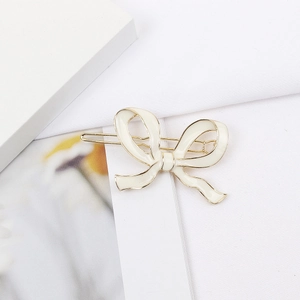 Barrette à cheveux minimaliste en métal doré avec nœud en émail crème sur carte